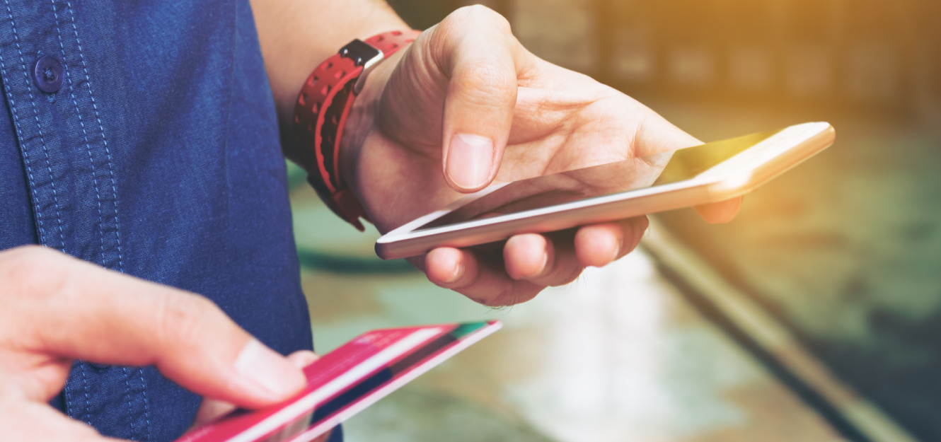 a man holding his phone and credit card