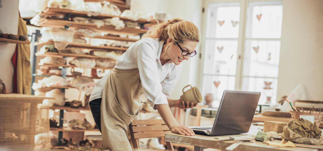 a woman standing and looking at her computer