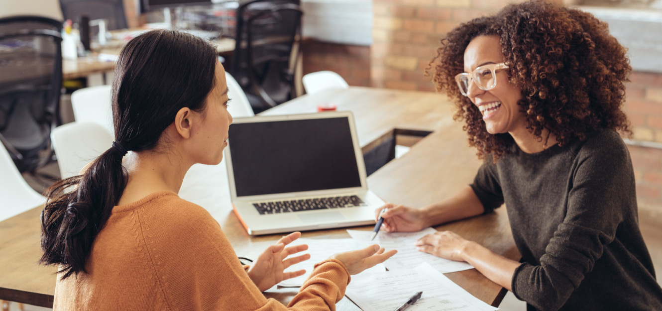 two women looking over paperwork at a desk