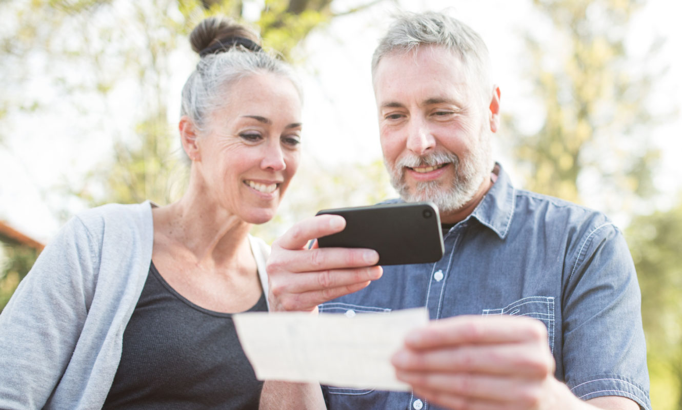 a couple using their mobile banking app to deposit a check